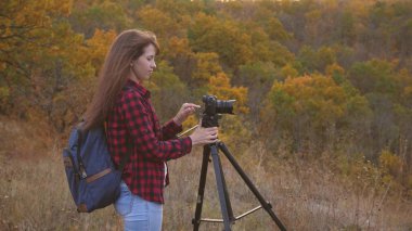 Kameralı kız gezgin doğanın güzel fotoğraflarını çekiyor. Genç, bağımsız bir kadın turist fotoğrafçısı, profesyonel bir dijital kamerayla güzel bir sonbahar manzarasını fotoğraflıyor. seyahat kavramı