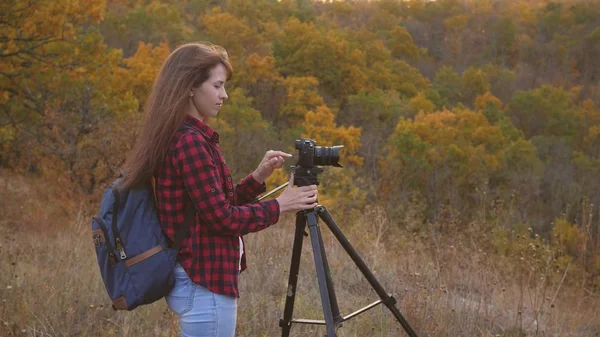 Girl traveler with a camera takes beautiful photos of nature. Young independent female tourist photographer, photographs a beautiful autumn landscape with a professional digital camera. travel concept — Stock Photo, Image