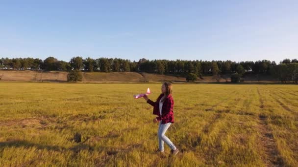 Mädchen startet ein Flugzeug in den Himmel und lächelt. ein Teenager träumt davon zu fliegen und Pilot oder Astronaut zu werden. Glückliches Mädchen rennt mit Spielzeugflugzeug aufs Feld. — Stockvideo