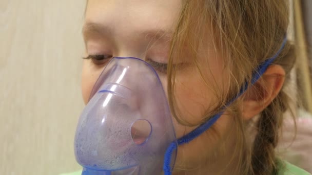 The child is sick and breathes through an inhaler. close-up. little girl is treated with an inhalation mask on her face in a hospital. Baby treats influenza by inhaling vapors when inhaled. — ストック動画