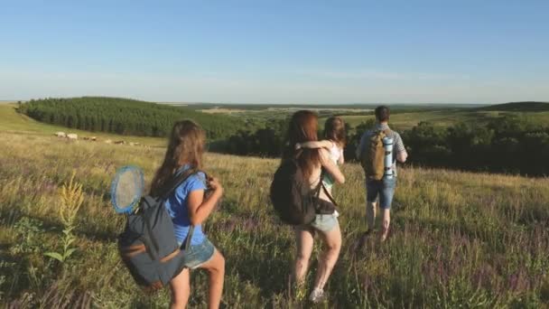 Teamwork resenärer. Familj till turister med barn på landsbygden. Resenärer beundrar vacker natur och natur. Lagarbete för turister. resenärer gå med ryggsäckar genom ängen. — Stockvideo