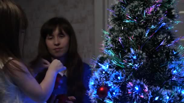 Bebé y mamá cuelgan un juguete de bola roja en el árbol de Navidad. concepto de infancia feliz. niño y madre decoran el árbol con bolas de Navidad. niño pequeño y un padre están jugando junto al árbol de Navidad . — Vídeo de stock