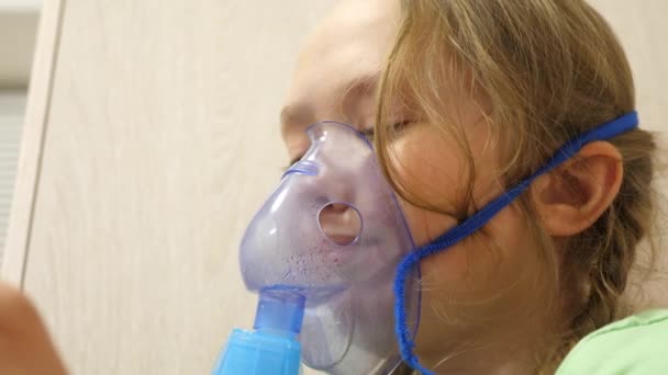 Child with tablet is sick and breathes through an inhaler. close-up. little girl treated with an inhalation mask on her face in hospital. Toddler treats flu by inhaling inhalation vapor. — Stock Video