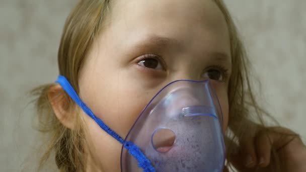 Çocuk hasta ve astım spreyinden nefes alıyor. Yakın plan. Hastanede küçük bir kız yüzünde solunum maskesi ile tedavi ediliyor. Bebek, soluduğunda buhar soluyarak gribi tedavi eder.. — Stok video