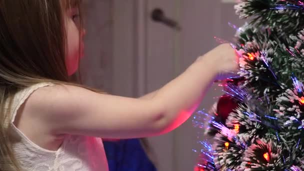Baby en mama hangen een rode bal speelgoed aan de kerstboom. Gelukkige kindertijd concept. kind en moeder versieren boom met kerstballen. klein kind en een ouder spelen bij kerstboom. — Stockvideo