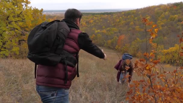 Trabajo en equipo de turistas. Los escaladores ayudan a un amigo a levantarse extendiendo una mano amiga. dos turistas en la cima de la montaña. Los viajeros en otoño en la colina admiran hermosos paisajes. concepto de turismo deportivo . — Vídeos de Stock