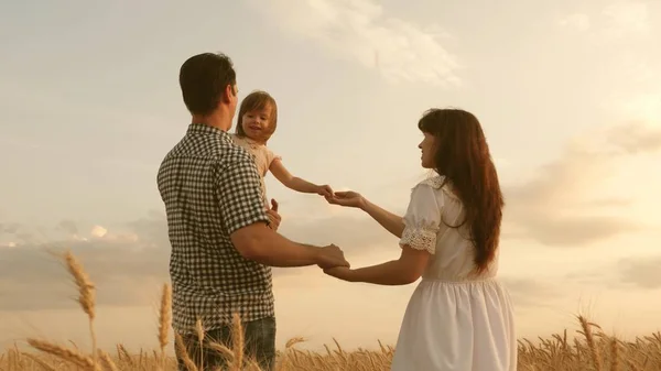 Barnet reser över fältet med sin familj. barn och föräldrar leker. lycklig familj och barndom koncept. Glad bebis i famnen på far och mor. liten dotter, pappa och mamma leker på ett vetefält — Stockfoto