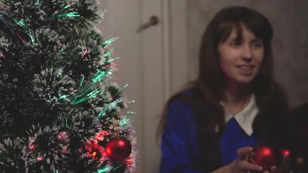 Çocuk ve anne Noel toplarıyla ağacı süslerler. Bebek ve anne Noel ağacına kırmızı bir top oyuncağı asıyorlar. Mutlu çocukluk kavramı. Küçük çocuk ve bir ebeveyn Noel ağacının yanında oynuyorlar.. — Stok video