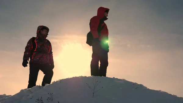Путешественники на снежной горе ориентируются по местности и выбирают направление движения. Аляскинские путешественники поднимаются на вершину снежного холма. командная работа людей. работа в команде, победа и успех . — стоковое фото