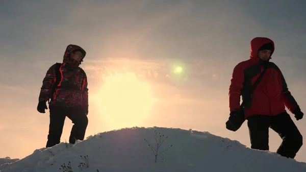 Les voyageurs sur une montagne enneigée sont guidés par le terrain et choisissent la direction du mouvement. Les voyageurs de l'Alaska vont au sommet d'une colline enneigée. le travail d'équipe des gens. travail d'équipe, victoire et succès . — Photo