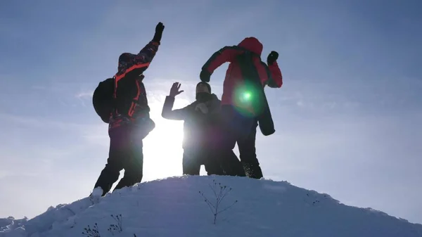 Viajantes se encontraram no topo do sucesso. Os turistas vêm ao topo da colina nevada e alegram-se com a vitória contra o pano de fundo de um pôr-do-sol amarelo. trabalho em equipa e vitória. trabalho em equipe de pessoas em condições difíceis — Fotografia de Stock