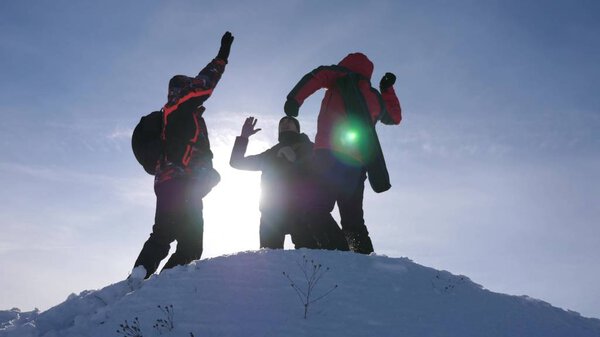 travelers met on top of success. Tourists come to top of snowy hill and rejoice at victory against backdrop of a yellow sunset. teamwork and victory. team work of people in difficult conditions