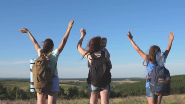 Mujeres viajeros levantan la mano y se regocijan. Mamá e hijos son turistas. Viajeros de trabajo en equipo. concepto de aventura. grupo de turistas viaja a través de un campo de flores y disfruta de la naturaleza desde la montaña . — Vídeos de Stock