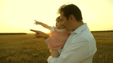 Mutlu aile ve çocukluk kavramı. Baba kızlarıyla parkta oynuyordu. Anne ve baba gün batımında kucağında küçük bir kızla oynuyorlar. Aile gün batımında bir çocukla yürüyor..