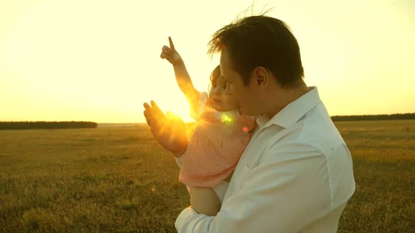 Mutlu aile ve çocukluk kavramı. Baba kızlarıyla parkta oynuyordu. Anne ve baba gün batımında kucağında küçük bir kızla oynuyorlar. Aile gün batımında bir çocukla yürüyor.. — Stok fotoğraf