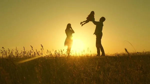 Criança, pai e mãe brincam no prado ao sol. conceito de uma infância feliz. mãe, pai e filha caminhando em um campo ao sol. Feliz família jovem. conceito de uma família feliz . — Fotografia de Stock