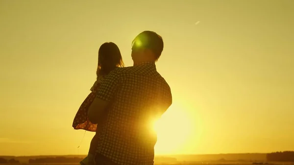 Vader geliefde kind in haar armen danst tijdens de vlucht en lacht. Gelukkige baby speelt met zijn vader bij zonsondergang. Silhouet van een man en een kind. Gezinsconcept — Stockfoto