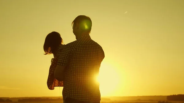 Vader geliefde kind in haar armen danst tijdens de vlucht en lacht. Gelukkige baby speelt met zijn vader bij zonsondergang. Silhouet van een man en een kind. Gezinsconcept — Stockfoto