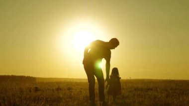 Küçük kız ve baba el ele tutuşarak sahada dolaşıyorlar. Çocuk babasının elini tutuyor. Baba ve bebek parkta dinleniyorlar. Çocuk babasıyla oynuyor. Mutlu aile ve çocukluk kavramı