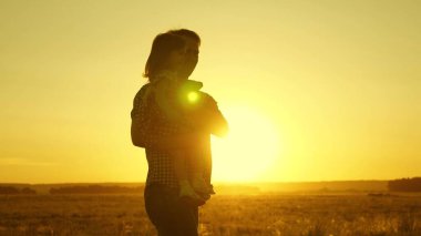 Babası kucağındaki sevgili çocuğu uçarken dans eder ve güler. Mutlu bebek gün batımında babasıyla oynuyor. Bir adam ve bir çocuğun silueti. Aile kavramı