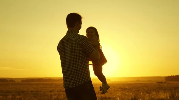 Papa enfant bien-aimé dans ses bras danse en fuite et rit. Happy baby joue avec son père au coucher du soleil. Silhouette d'un homme et d'un enfant. Concept de famille — Photo