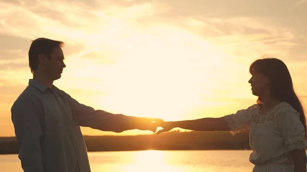 Hombre y mujer cariñosos bailan en brillantes rayos de sol en el fondo del lago. Pareja joven bailando al atardecer en la playa. Feliz chico y chica vals en la noche en el parque de verano . —  Fotos de Stock