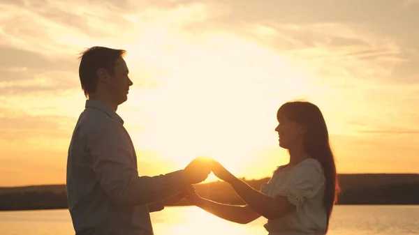 Homem amoroso e mulher dançam em raios brilhantes de sol no fundo do lago. Casal jovem dançando ao pôr do sol na praia. Feliz cara e menina valsa à noite no parque de verão . — Fotografia de Stock