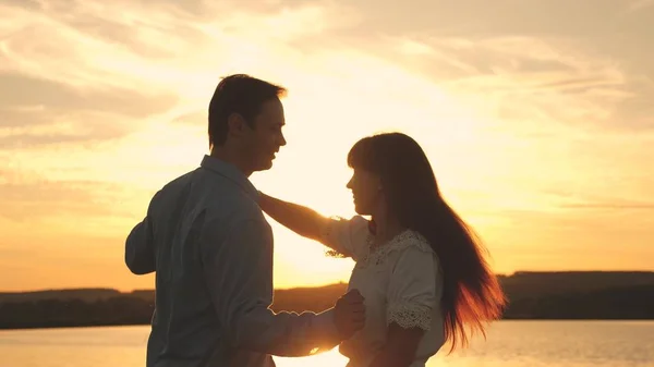 Amare l'uomo e la donna danzano in raggi di sole sullo sfondo del lago. Giovane coppia che balla al tramonto sulla spiaggia. Felice ragazzo e ragazza valzer la sera nel parco estivo . — Foto Stock