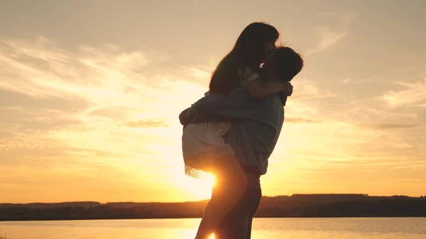 Amare l'uomo e la donna danzano in raggi di sole sullo sfondo del lago. coppia che balla al tramonto sulla spiaggia. Felice ragazzo e ragazza valzer la sera nel parco estivo . — Foto Stock