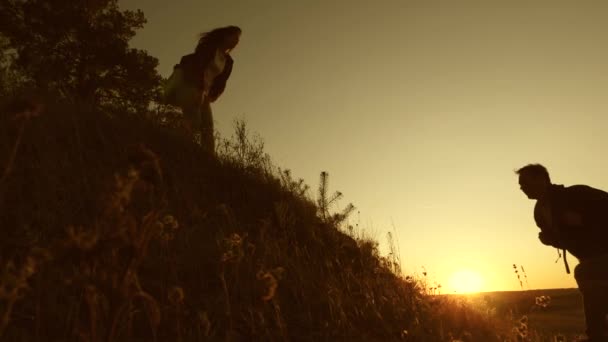 Free Woman traveler holds out his hand to the traveler a man climbing to the top of the hill. teamwork tourists. adventure and travel concept. Tourists climb the mountain at sunset, holding hands. — 图库视频影像