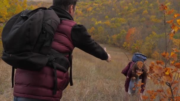 Climbers help a friend rise by holding out a helping hand to a friend. teamwork of tourists. two tourists on top of mountain. Travelers in autumn on hill admire beautiful scenery. sport tourism — Stockvideo