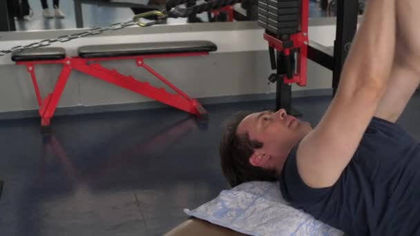 Training in a fitness club. Strong muscular athlete in a t-shirt and shorts performs exercises while Pullover on lower block lying on a horizontal bench. gym workout. Sport lifestyle concept. — Stok video