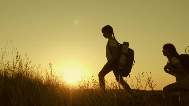 Free girls and women and a man go camping. children and mom, dad with backpacks travel through the mountains in the sun. joint work of tourists. Slow motion. teamwork travelers — Wideo stockowe