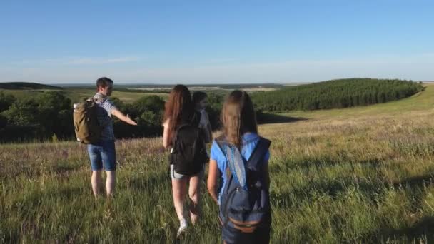 Teamwork of tourists. travelers admire the beautiful scenery and nature. travelers go with backpacks through the meadow. Family of tourists with children in the countryside. family tourism concept — Stock Video
