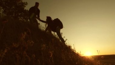 Özgür gezginler gün batımında el ele tutuşarak dağdan inerler. Erkek turist, tepeden inen dişi bir yolcunun elini tutuyor. İş adamlarının işbirliği.