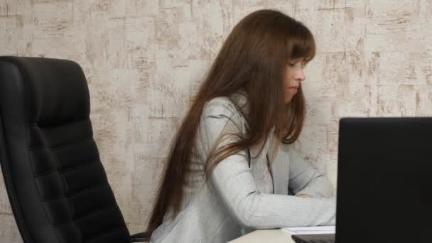 아름다운 비지니스 여성 이 사무실에서 서류 작업을 하고 있습니다. 직장에서 자유 로운 사업을 하는 여성. 컴퓨터 사무실에서 일하는 어린 소녀입니다. 피곤 한 직원. — 비디오