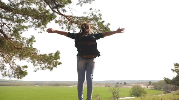 Gratis kvinna turist på semester i skogen. lycklig kvinna resenär med ryggsäck lyfter armarna åt sidorna, njuter av naturen. Flickan reser i parken. hälsosam livsstil koncept. — Stockfoto