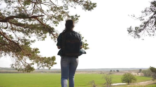 Gratis kvinna turist på semester i skogen. lycklig kvinna resenär med ryggsäck lyfter armarna åt sidorna, njuter av naturen. Flickan reser i parken. hälsosam livsstil koncept. — Stockfoto