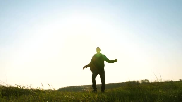 Funny traveler with backpacks walking and fooling around. a tourist with backpack walks across the field in the bright rays of the sun and laughs. Slow motion. adventure and travel concept — Stock Video