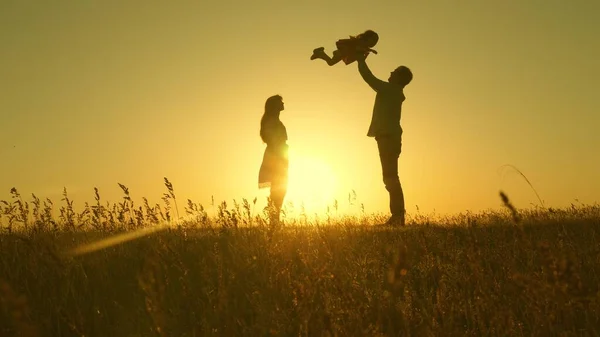 child, dad and mom play in the meadow in the sun. concept of a happy childhood. mother, father and little daughter walking in a field in the sun. Happy young family. concept of a happy family.