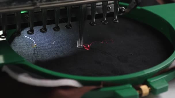 CNCロボットミシン。黒い布に赤い糸が付いた自動機械刺繍パターンです。ロボット工学は、生産ラインの調整に役立ちます。コンピューターコントロールミシン — ストック動画