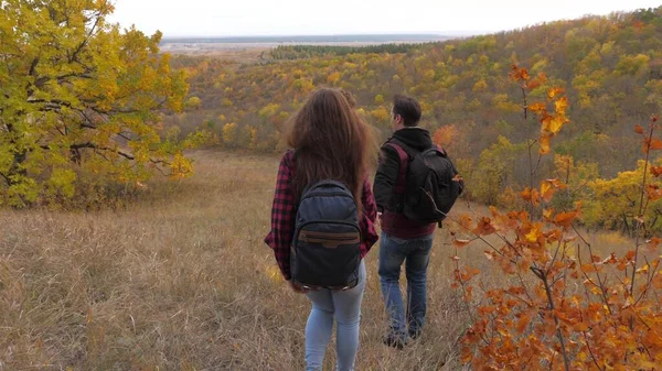 Teamwork Reisenden. Touristen Mann und Frau reisen Händchen haltend. Teamwork. Touristen gehen den Hügel hinunter in den wunderschönen Herbstwald. Reisende, Männer und Frauen Händchen haltend genießen die Schönheit der — Stockfoto