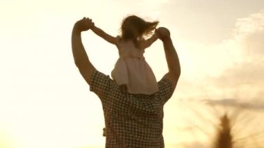 Çocuk ve baba olgunlaşan buğday tarlasında oynuyorlar. Küçük kız babasının omuzlarında. Bebek ve babası sahada seyahat ediyor. Çocuk ve ebeveyn doğada oynuyorlar. Mutlu aile ve çocukluk kavramı