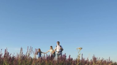 Gezginler el ele gider. Turistlerin takım çalışması. Turistler sırt çantalarıyla çayırlarda dolaşırlar. Kırsalda çocuklu bir turist ailesi. Zafere doğru hareket. ekolojik turizm