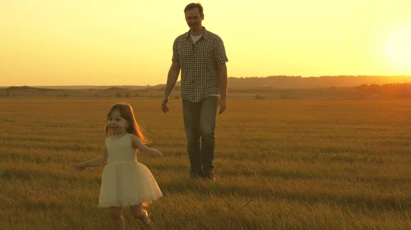 Papa en baby in het park. Gelukkige kindertijd concept. Kleine dochter loopt met papa in de wei. kind speelt in de wei met zijn vader. kind loopt op het gras. familie wandelingen in de avond buiten de stad. — Stockfoto