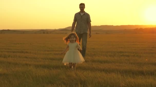 Dad and baby in park. happy childhood concept. Little daughter walks with dad in meadow. child plays in the meadow with his father. child runs on the grass. family walks in evening out of town. — Stock Video
