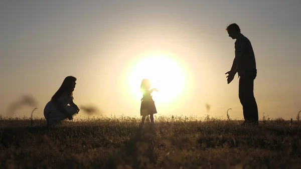 Rodiče si hrají se svou dcerou. Šťastné dítě jde od táty k mámě. Šťastné dětství. rodiče se učí venčit malé dítě. holčička dělá své první kroky na slunci, zpomaluje. — Stock fotografie