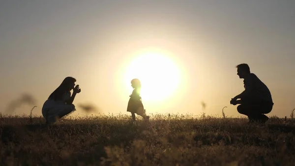 Föräldrarna leker med sin lilla dotter. mamma och pappa leker med sin dotter i solen. Happy baby går från pappa till mamma. ung familj på fältet med ett barn 1 år. familj Happiness Concept. — Stockfoto
