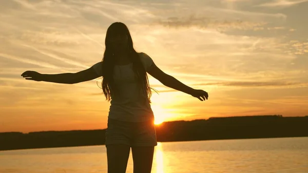 Молодая женщина танцует на закате. Свободная и веселая женщина. Счастливая девушка с длинными волосами танцует на закате на пляже и смеется. Медленное движение . — стоковое фото