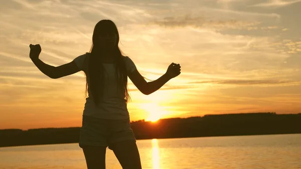 Ung kvinna som dansar på en solnedgång fest. Fri och glad kvinna. Lycklig flicka med långt hår dansar vid solnedgången på stranden och skrattar. Långsamma rörelser. — Stockfoto